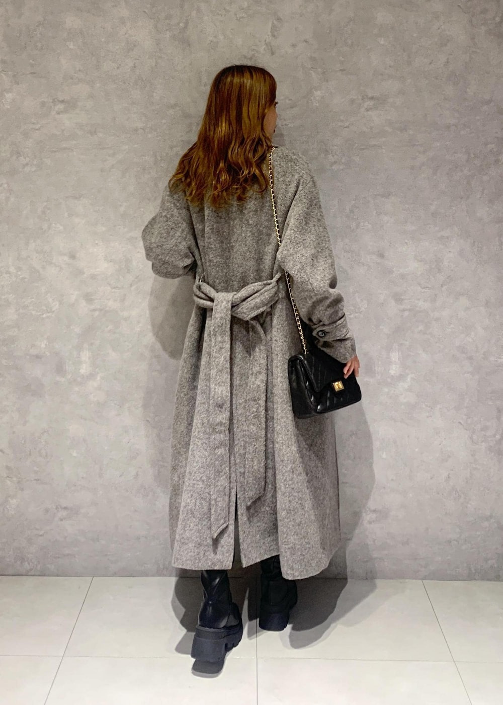 ブラック系のショルダーバッグ、ブラック系のブーツ、グレー系のステンカラーコートを着用したレディースの秋コーディネートの4枚目の写真