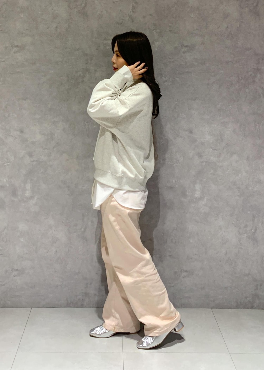 シルバー系のパンプス、ピンク系のデニムパンツ、ベージュ系のショルダーバッグを着用したレディースの冬コーディネートの4枚目の写真