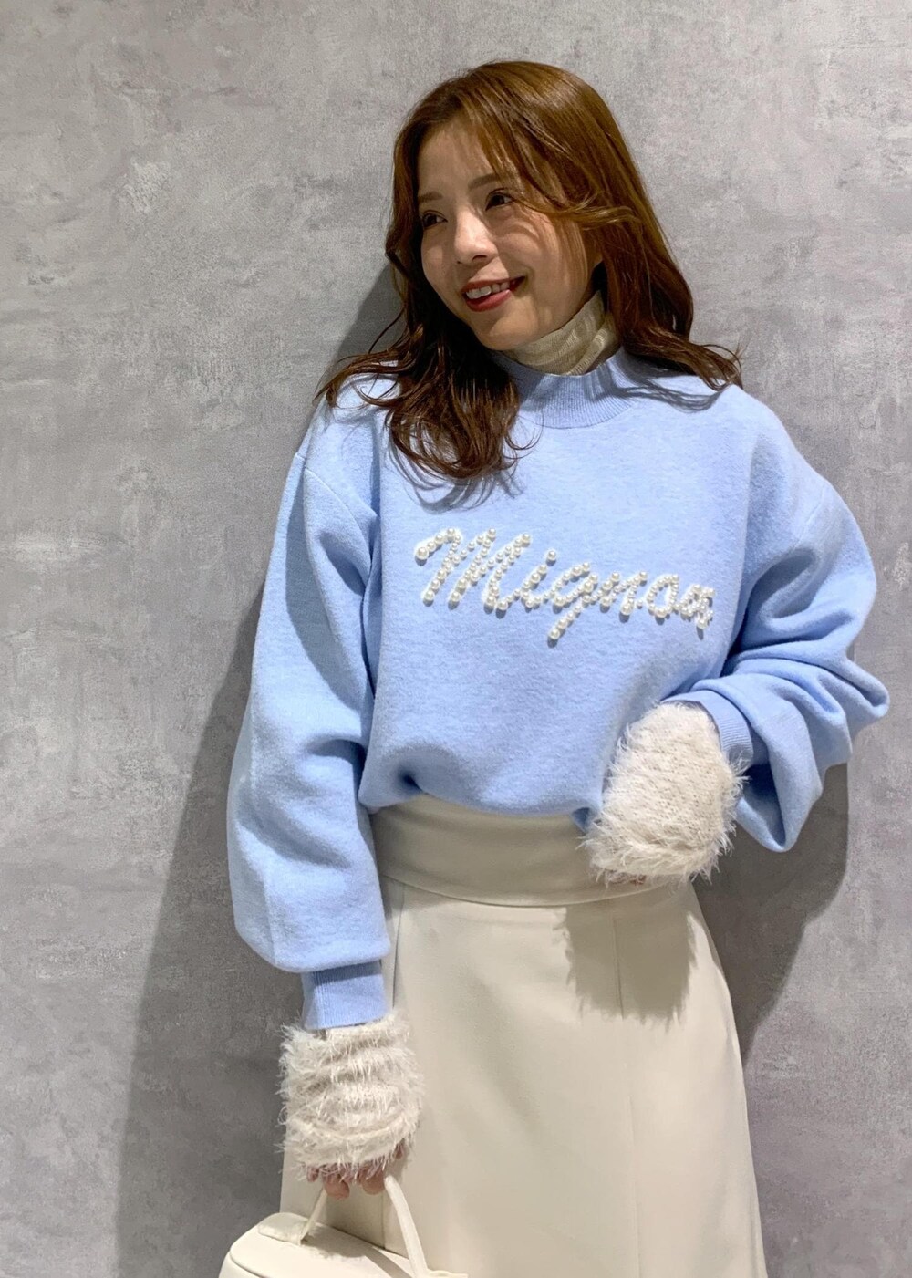 ホワイト系のニット/セーター、ホワイト系のブーツ、ホワイト系のハンドバッグを着用したレディースの冬コーディネートの7枚目の写真