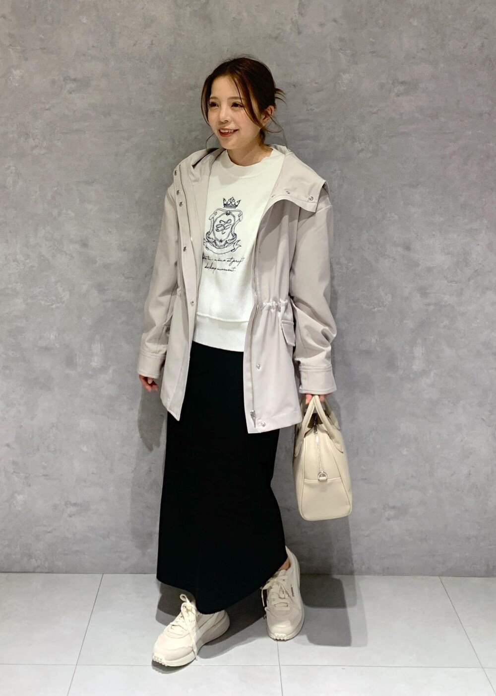 ブラック系のスカート、ベージュ系のボストンバッグ、グレー系のマウンテンパーカーを着用したレディースの春コーディネートの3枚目の写真