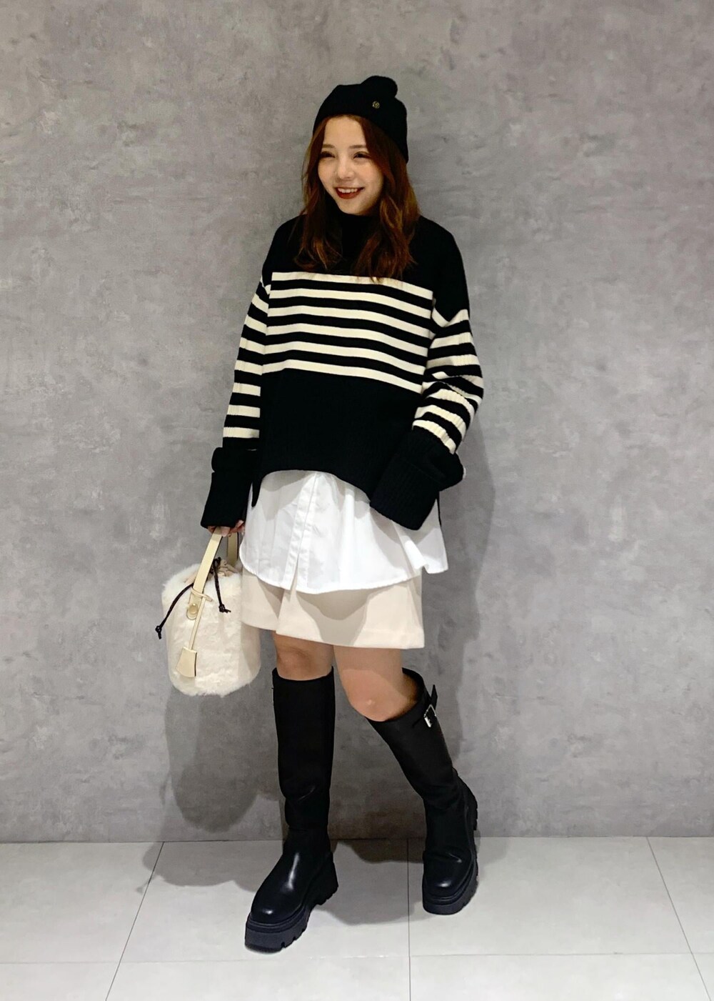 ブラック系のブーツ、ホワイト系のシャツ/ブラウス、ブラック系のニット/セーターを着用したレディースの秋コーディネートの2枚目の写真