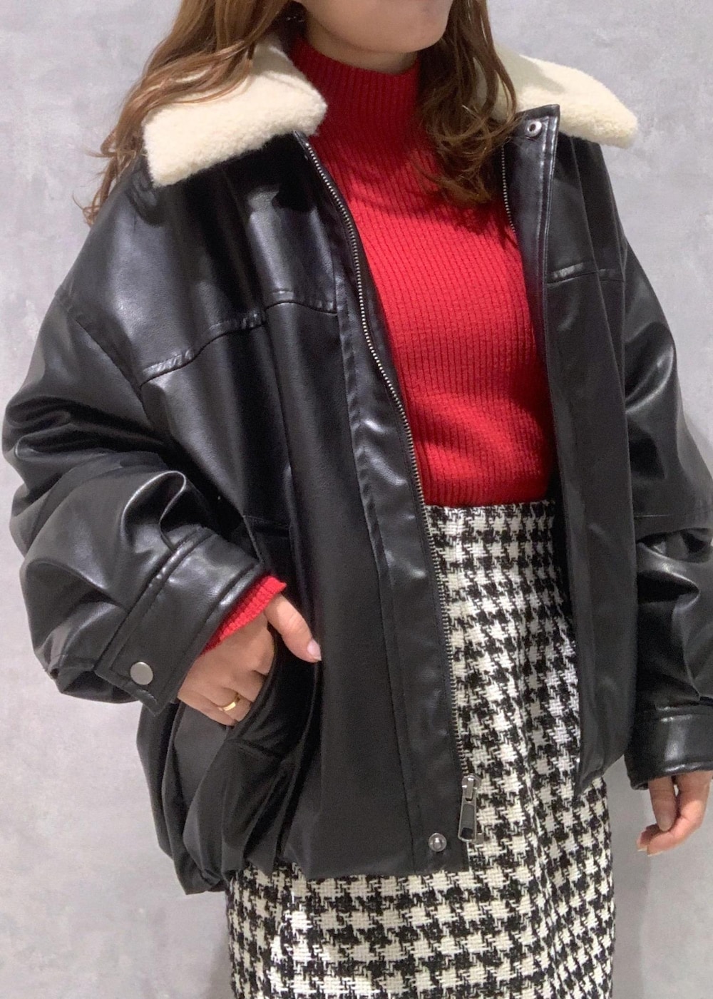 ブラック系のショルダーバッグ、ブラック系のブーツ、レッド系のニット/セーターを着用したレディースの冬コーディネートの9枚目の写真