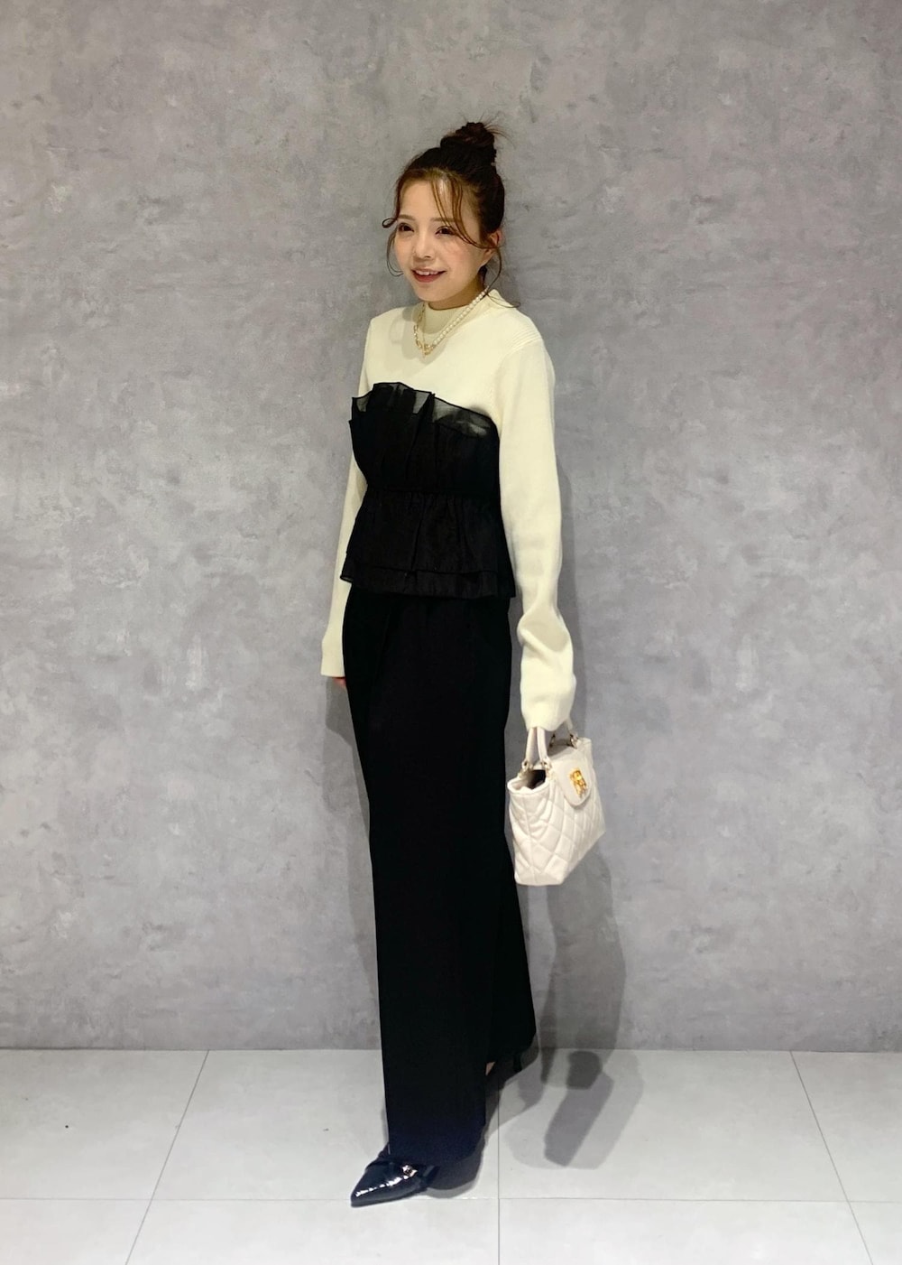 ブラック系のパンプス、ホワイト系のニット/セーター、ブラック系のスラックスを着用したレディースの冬コーディネートの3枚目の写真