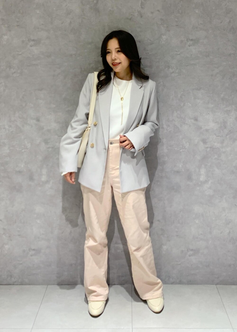 ホワイト系のハンドバッグ、ピンク系のデニムパンツ、ホワイト系のニット/セーターを着用したレディースの冬コーディネートの2枚目の写真