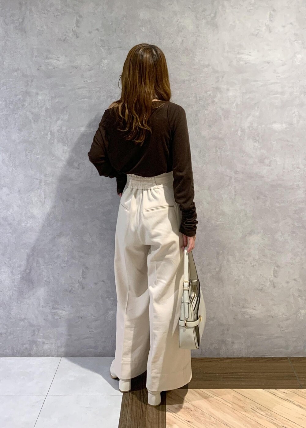 ホワイト系のブーツ、ホワイト系のハンドバッグ、ベージュ系のその他パンツを着用したレディースの秋コーディネートの5枚目の写真
