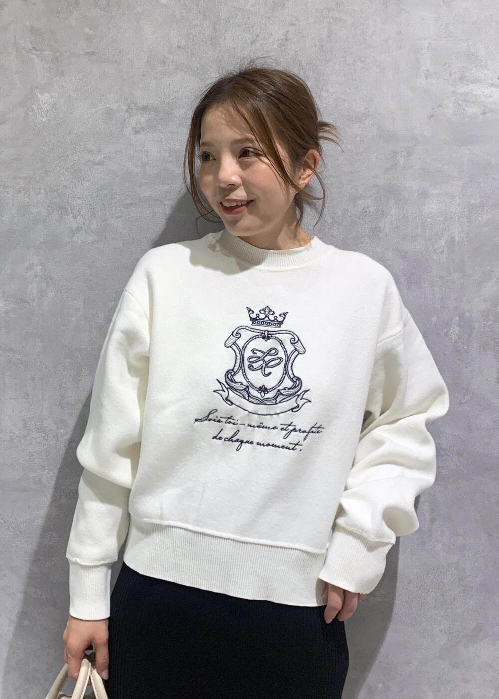 ブラック系のスカート、ベージュ系のボストンバッグ、ホワイト系のニット/セーターを着用したレディースの春コーディネートの6枚目の写真