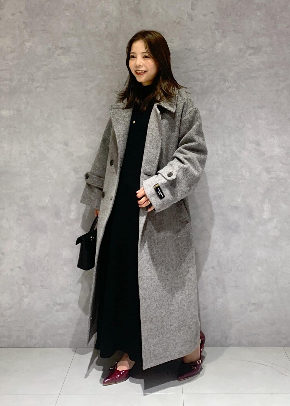 その他のショルダーバッグ、グレー系のステンカラーコート、ブラック系のワンピースを着用したレディースの秋コーディネートの2枚目の写真
