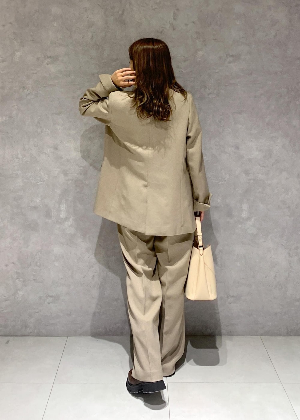 ブラウン系のブーツ、ベージュ系のショルダーバッグ、ベージュ系のスラックスを着用したレディースの秋コーディネートの4枚目の写真