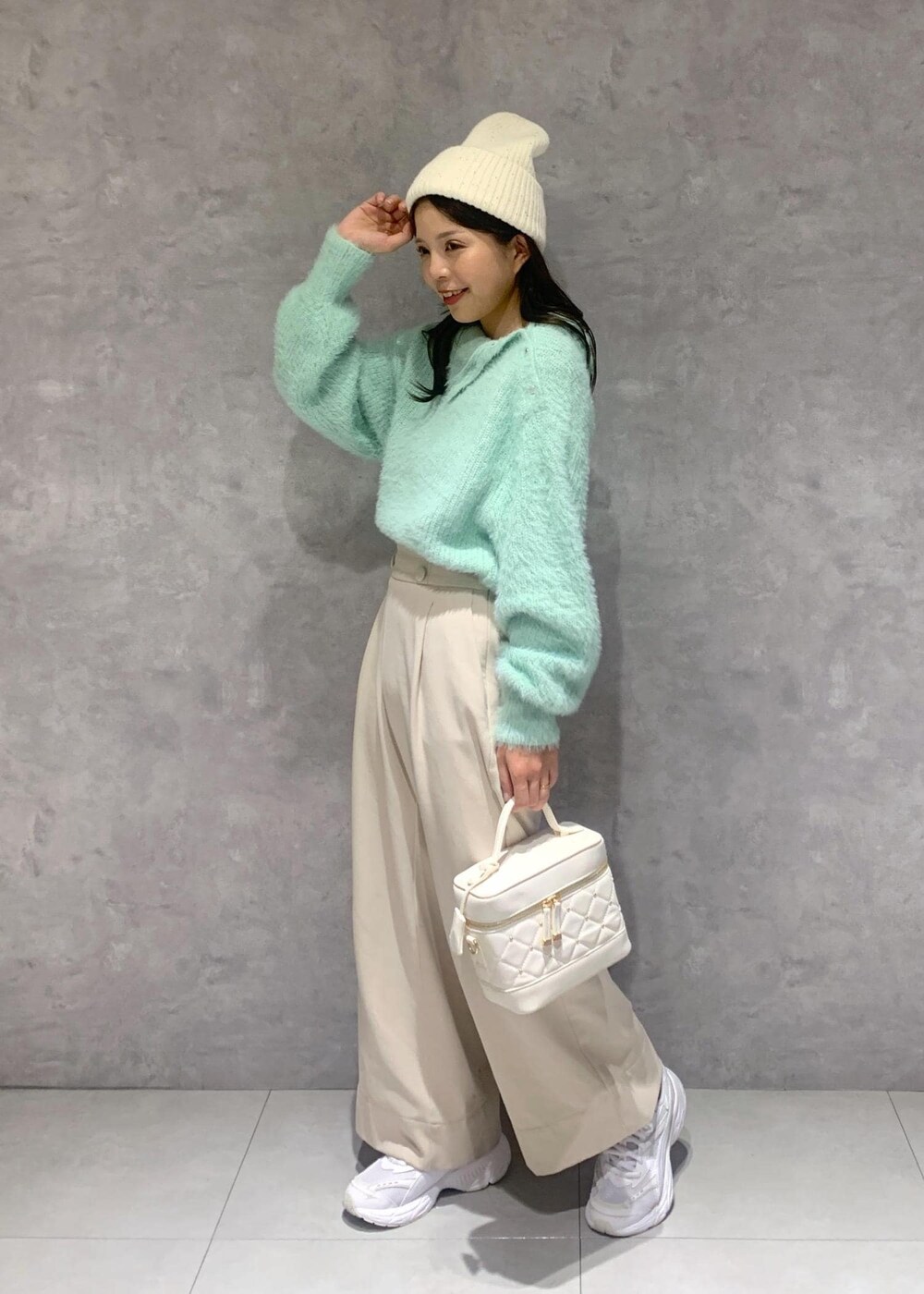 ホワイト系のハンドバッグ、ベージュ系のその他パンツ、グリーン系のニット/セーターを着用したレディースの冬コーディネートの3枚目の写真