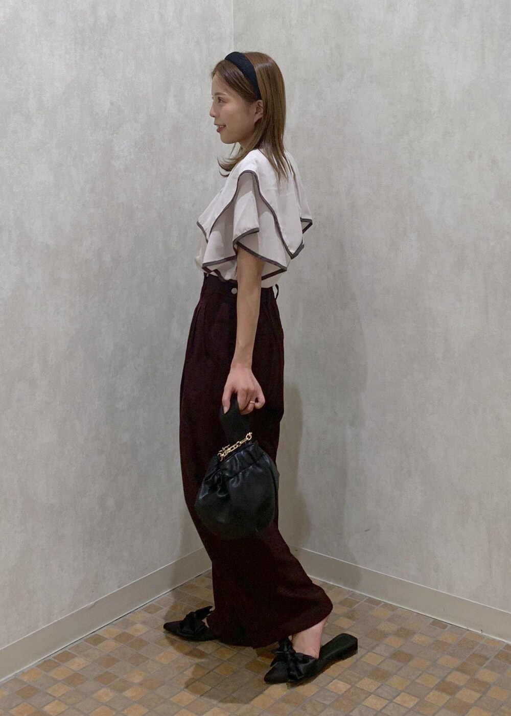 ブラウン系のスラックス、ブラック系のハンドバッグ、ブラック系のサンダルを着用したレディースの夏コーディネートの3枚目の写真