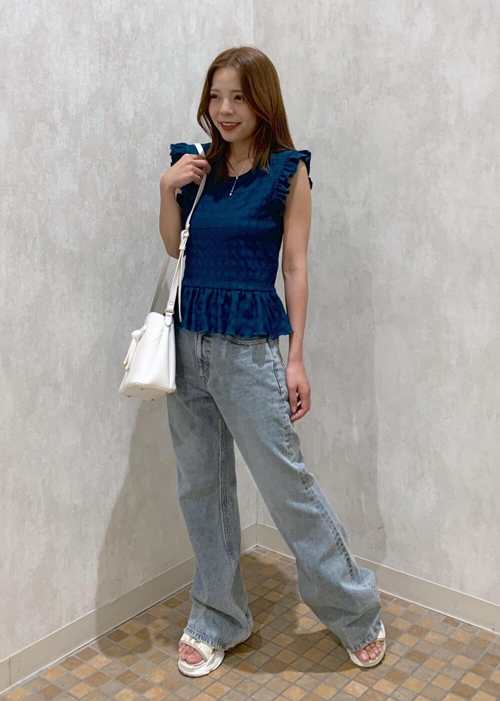 ベージュ系のサンダル、ホワイト系のショルダーバッグ、ブルー系のデニムパンツを着用したレディースの夏コーディネートの2枚目の写真