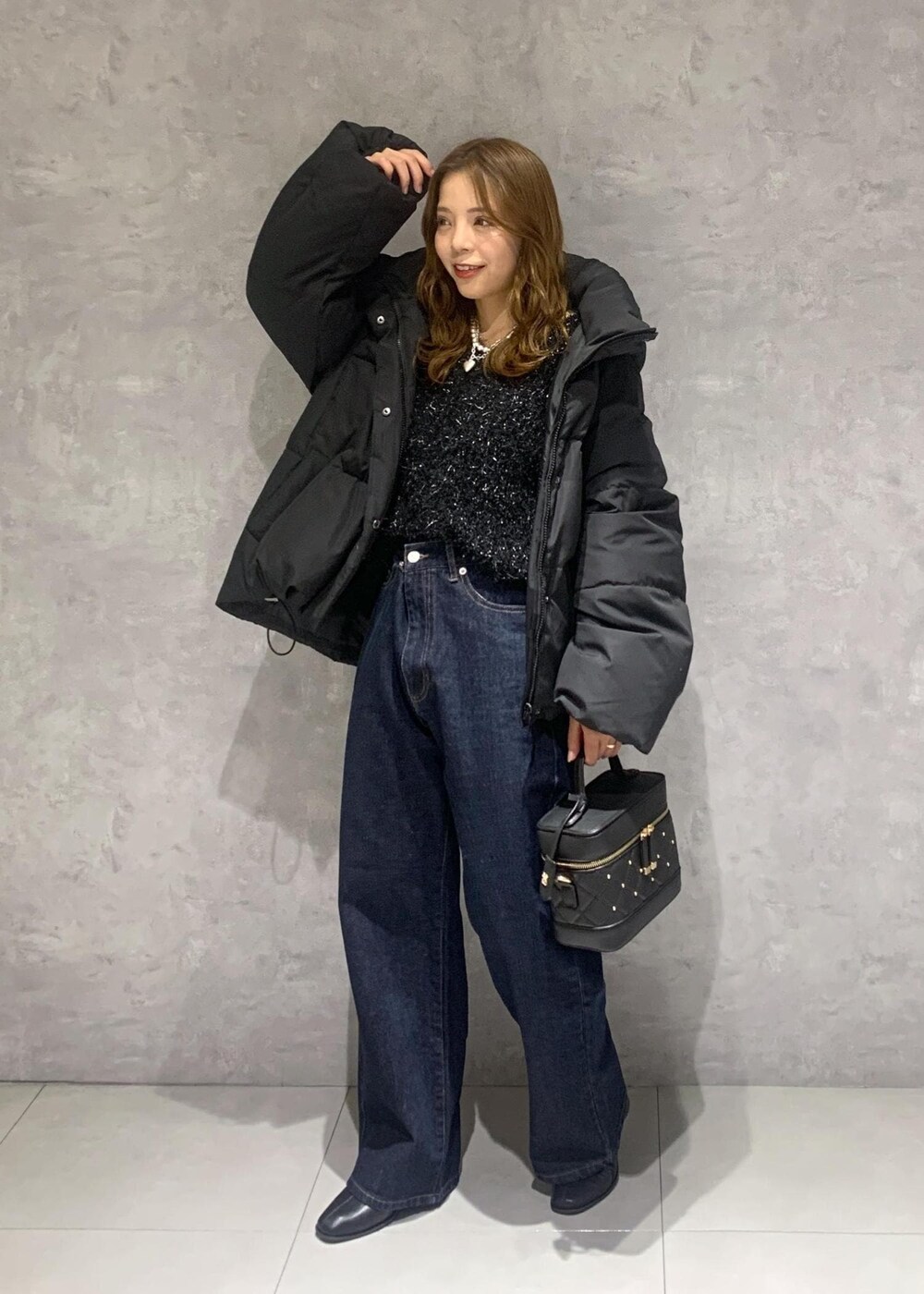 ブラック系のブーツ、ブルー系のデニムパンツ、ブラック系のハンドバッグを着用したレディースの冬コーディネートの3枚目の写真