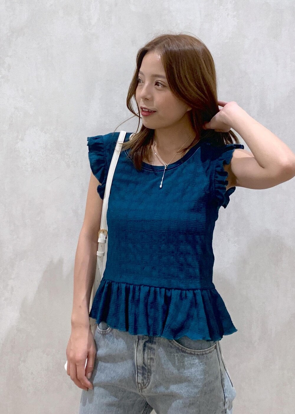 ベージュ系のサンダル、ホワイト系のショルダーバッグ、ブルー系のデニムパンツを着用したレディースの夏コーディネートの6枚目の写真