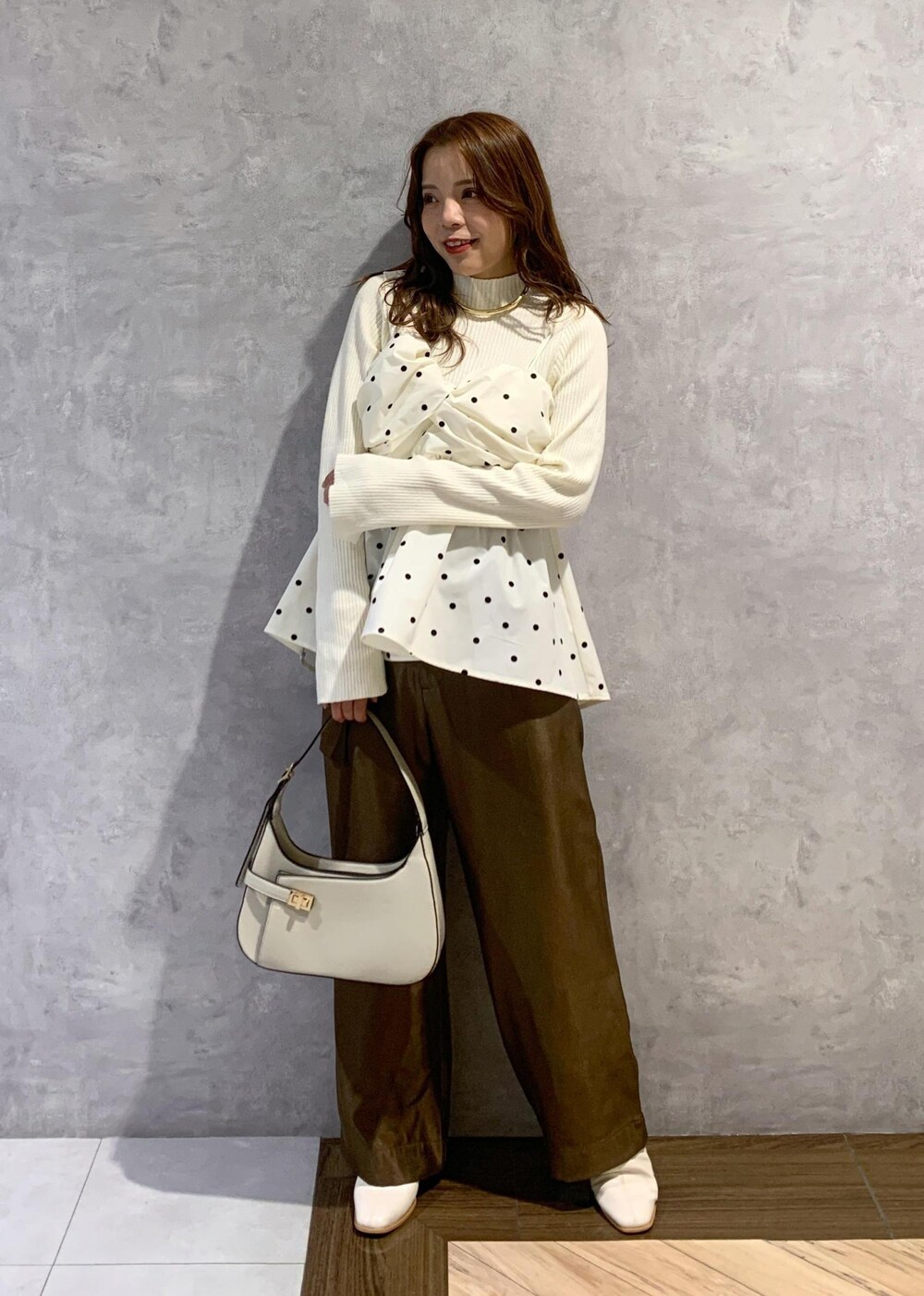 ホワイト系のブーツ、ホワイト系のニット/セーター、ホワイト系のハンドバッグを着用したレディースの冬コーディネートの2枚目の写真