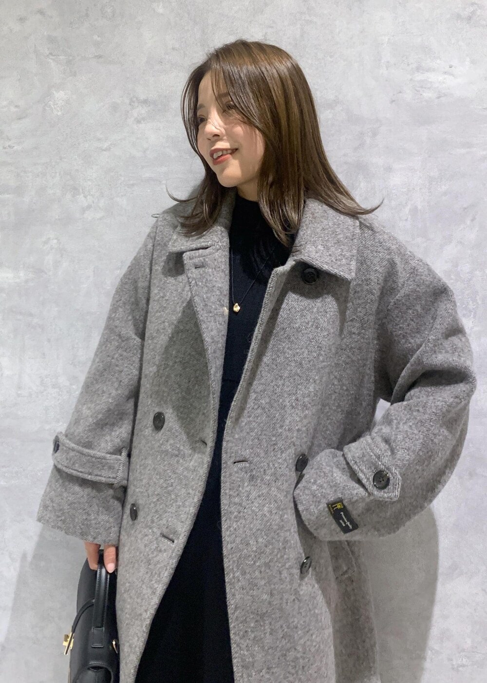 その他のショルダーバッグ、グレー系のステンカラーコート、ブラック系のワンピースを着用したレディースの秋コーディネートの5枚目の写真