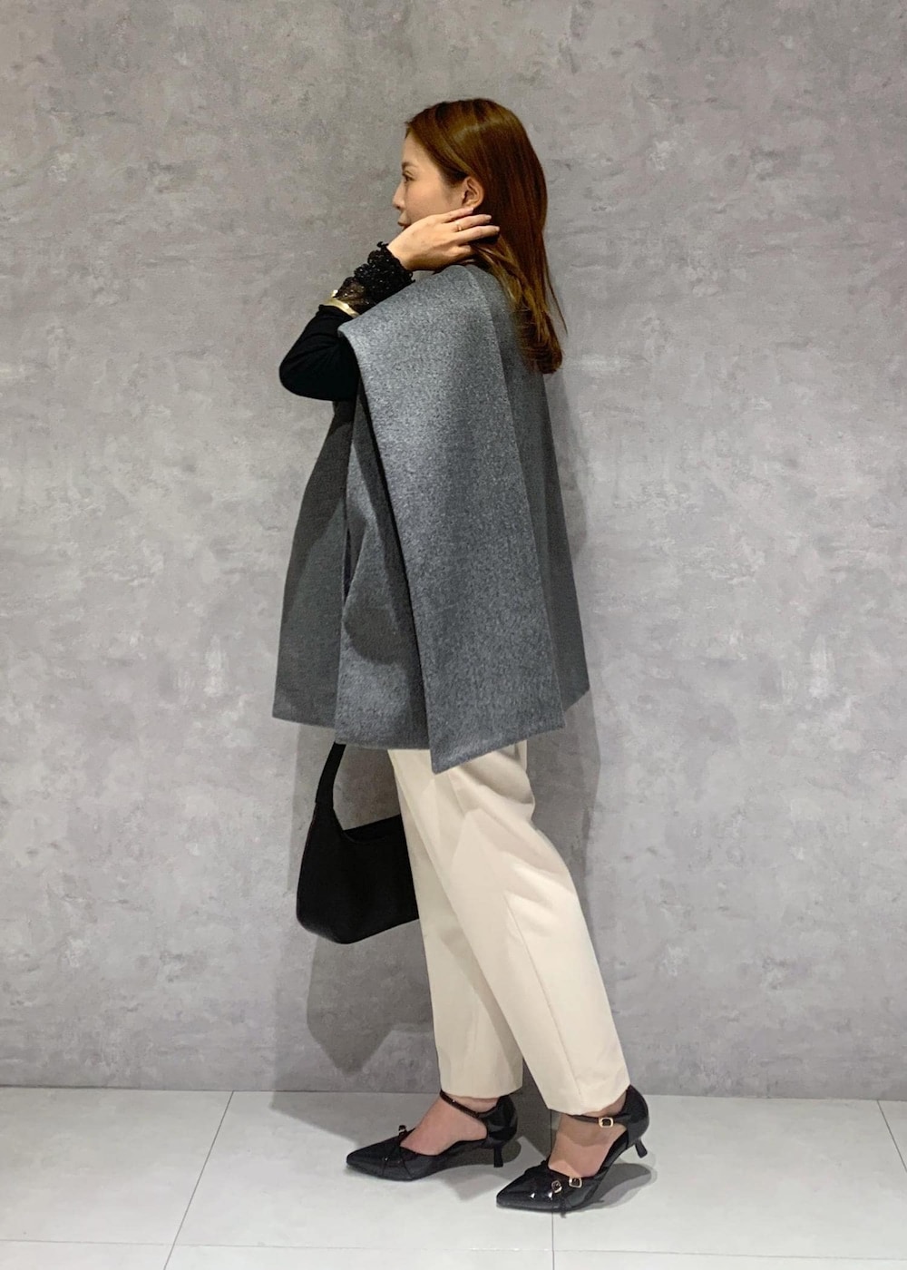 ブラック系のパンプス、グレー系のポンチョ、ブラック系のTシャツ/カットソーを着用したレディースの秋コーディネートの3枚目の写真