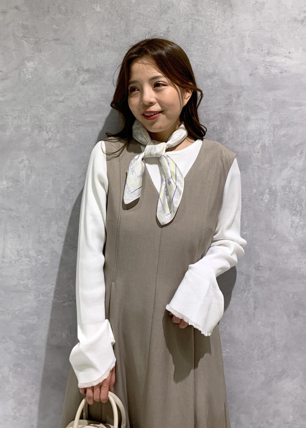 イエロー系のジャンパースカート、ホワイト系のニット/セーター、ホワイト系のローファーを着用したレディースの冬コーディネートの6枚目の写真