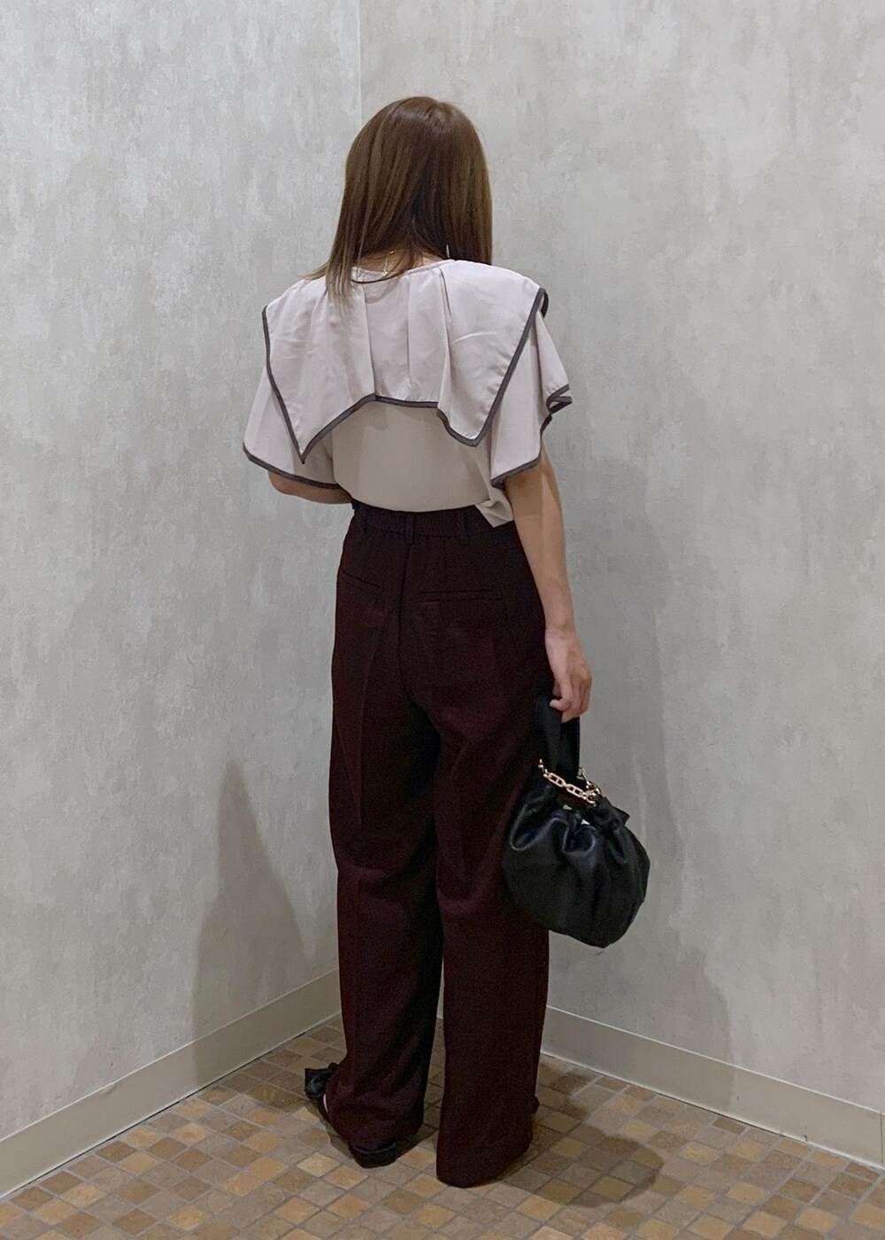 ブラウン系のスラックス、ブラック系のハンドバッグ、ブラック系のサンダルを着用したレディースの夏コーディネートの4枚目の写真