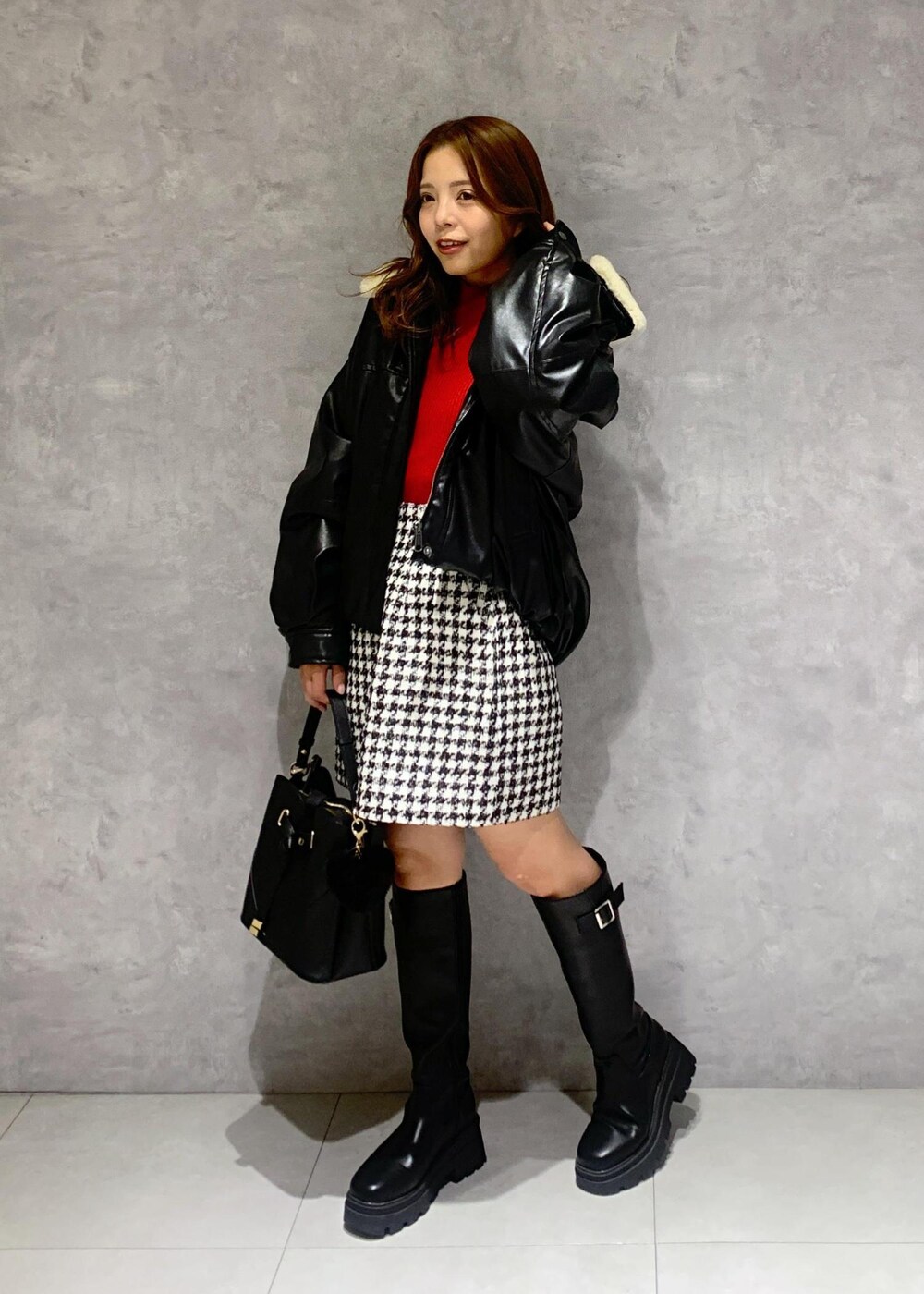 ブラック系のショルダーバッグ、ブラック系のブーツ、レッド系のニット/セーターを着用したレディースの冬コーディネートの3枚目の写真