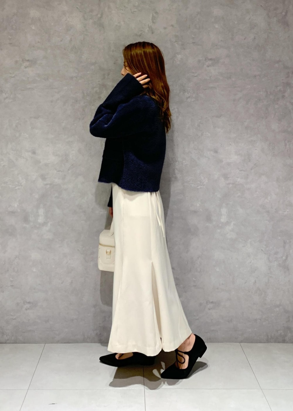 ブルー系のカーディガン/ボレロ、ホワイト系のハンドバッグ、ブラック系のパンプスを着用したレディースの秋コーディネートの4枚目の写真