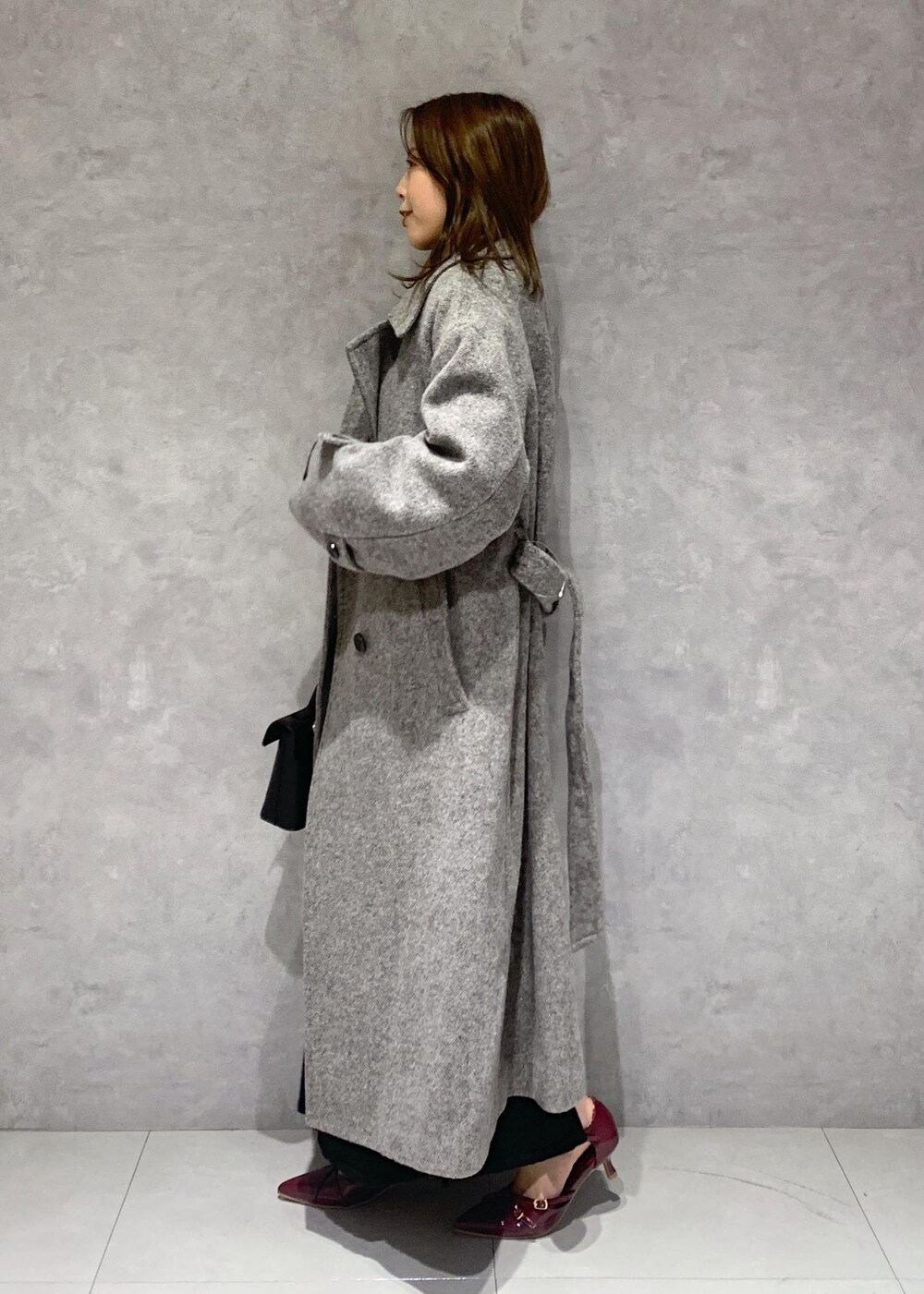 その他のショルダーバッグ、グレー系のステンカラーコート、ブラック系のワンピースを着用したレディースの秋コーディネートの3枚目の写真