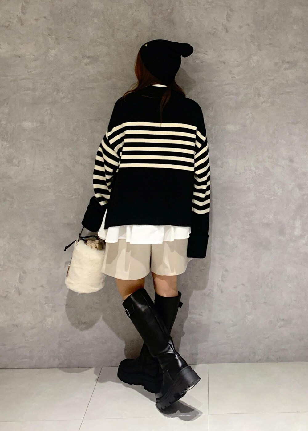 ブラック系のブーツ、ホワイト系のシャツ/ブラウス、ブラック系のニット/セーターを着用したレディースの秋コーディネートの4枚目の写真