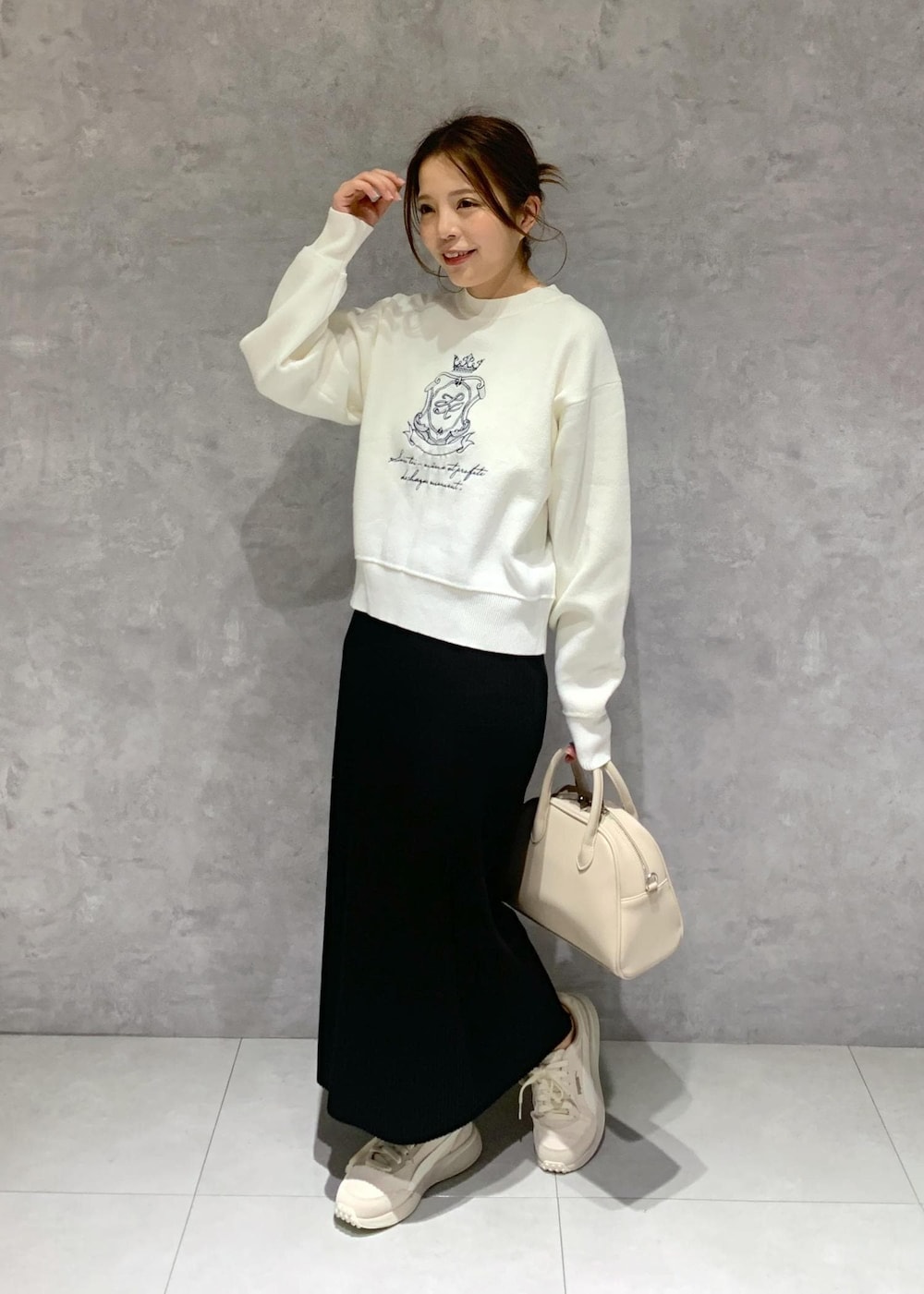 ブラック系のスカート、ベージュ系のボストンバッグ、ホワイト系のニット/セーターを着用したレディースの春コーディネートの3枚目の写真