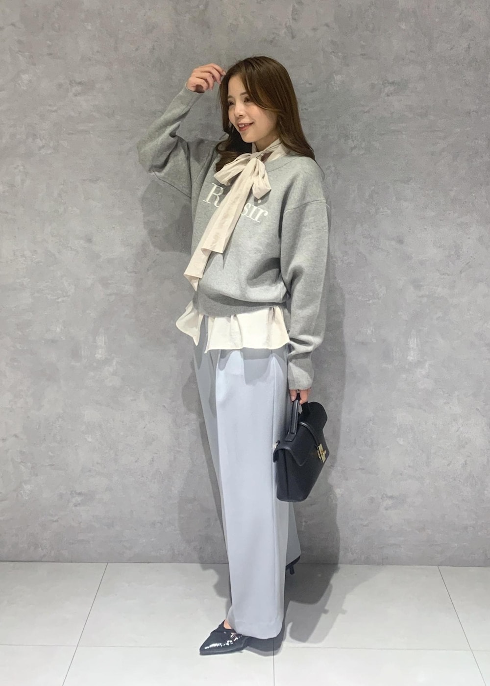 ブラック系のショルダーバッグ、ホワイト系のシャツ/ブラウス、ブルー系のスラックスを着用したレディースの冬コーディネートの3枚目の写真