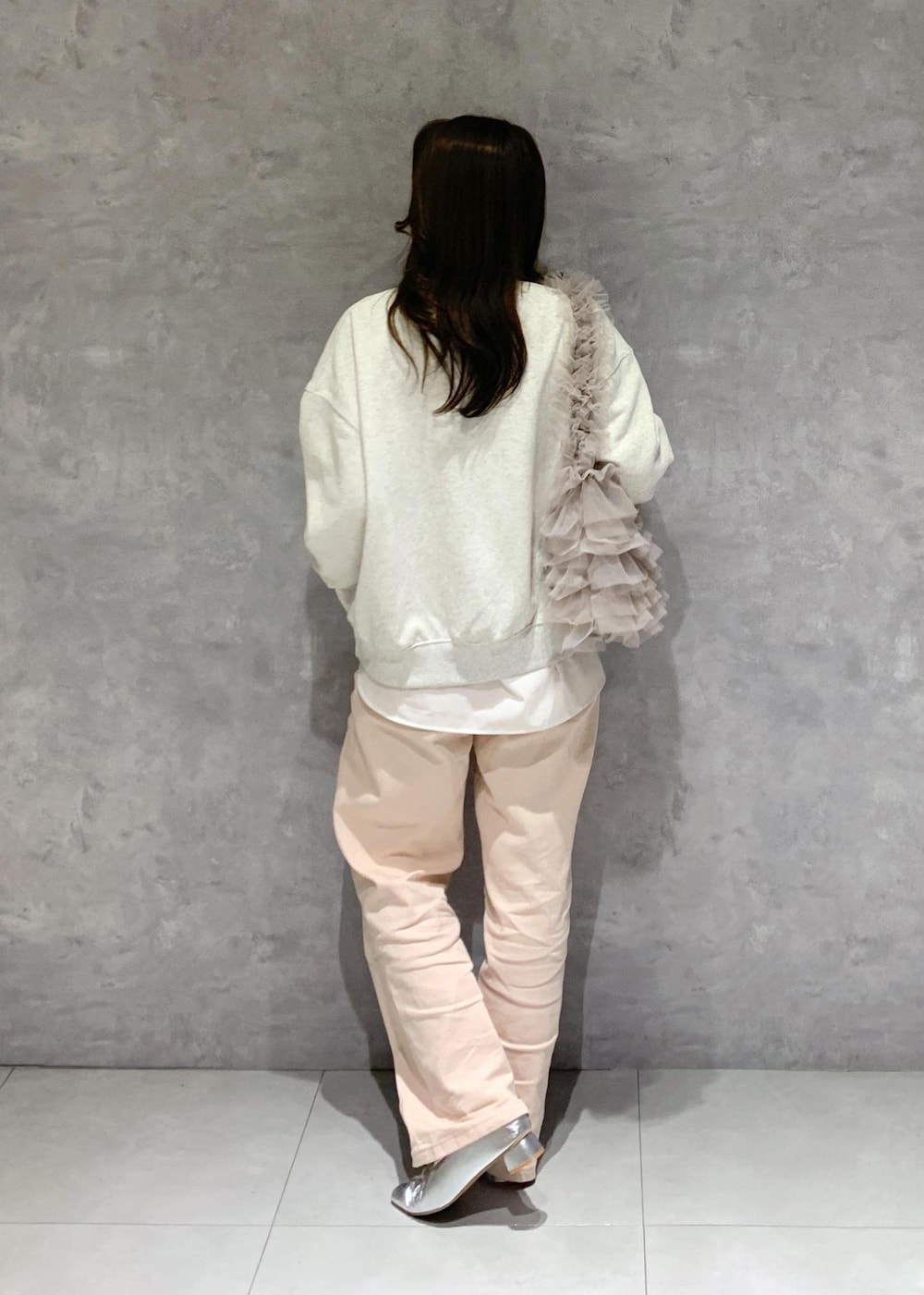 シルバー系のパンプス、ピンク系のデニムパンツ、ベージュ系のショルダーバッグを着用したレディースの冬コーディネートの5枚目の写真