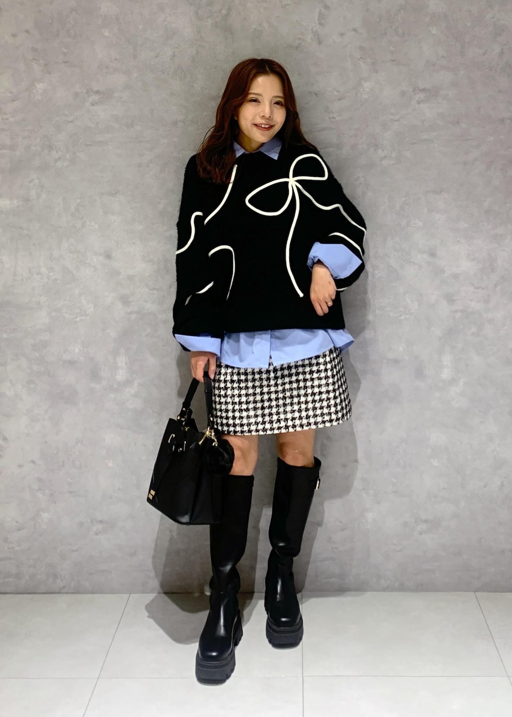 ブラック系のショルダーバッグ、ブラック系のブーツ、ブラック系のニット/セーターを着用したレディースの冬コーディネートの2枚目の写真