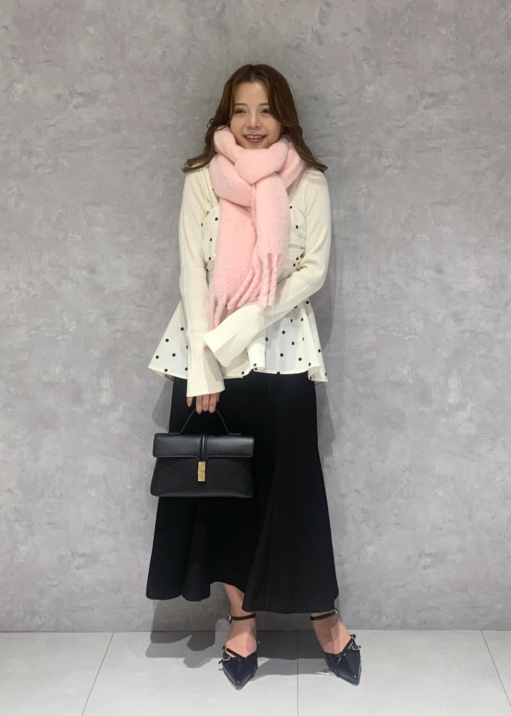 ブラック系のショルダーバッグ、ホワイト系のニット/セーター、ブラック系のスカートを着用したレディースの冬コーディネートの2枚目の写真