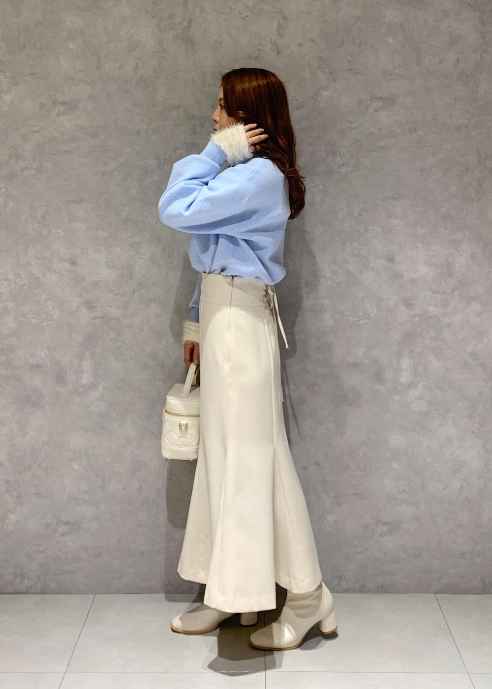 ホワイト系のニット/セーター、ホワイト系のブーツ、ホワイト系のハンドバッグを着用したレディースの冬コーディネートの4枚目の写真