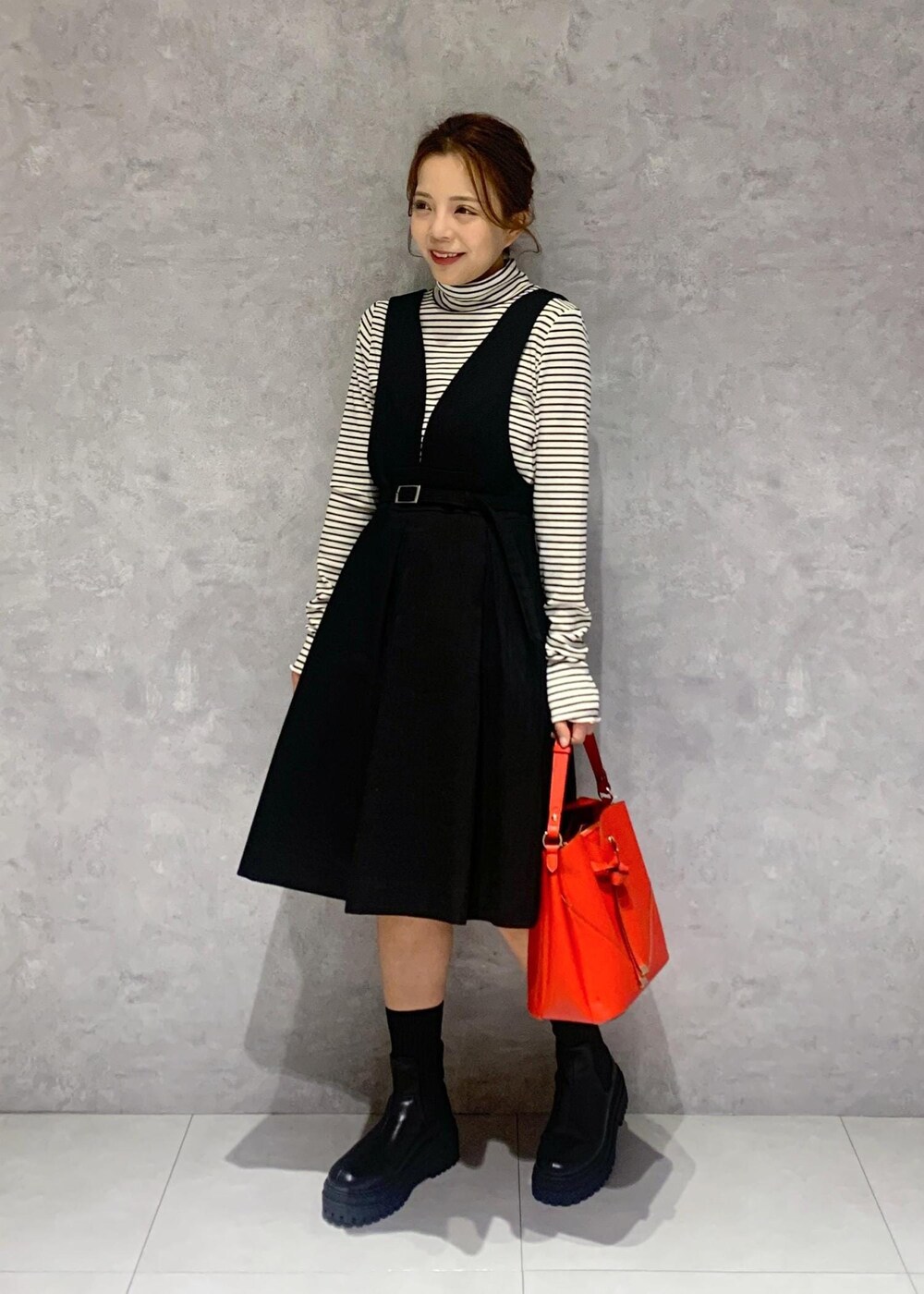 ブラック系のブーツ、レッド系のショルダーバッグ、ブラック系のワンピースを着用したレディースの冬コーディネートの6枚目の写真