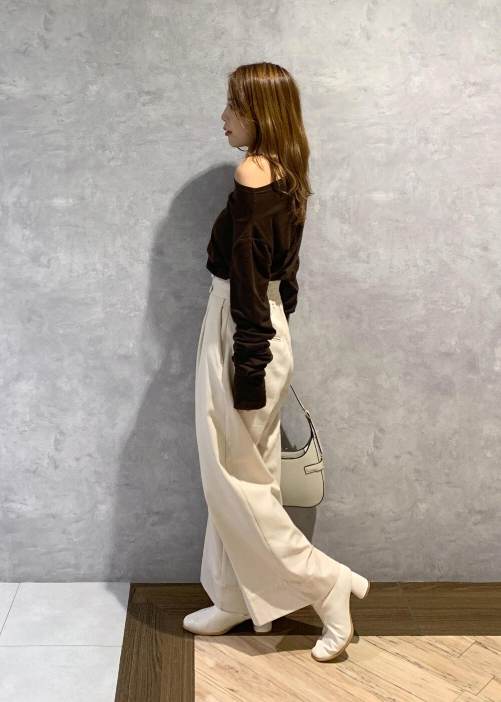 ホワイト系のブーツ、ホワイト系のハンドバッグ、ベージュ系のその他パンツを着用したレディースの秋コーディネートの4枚目の写真