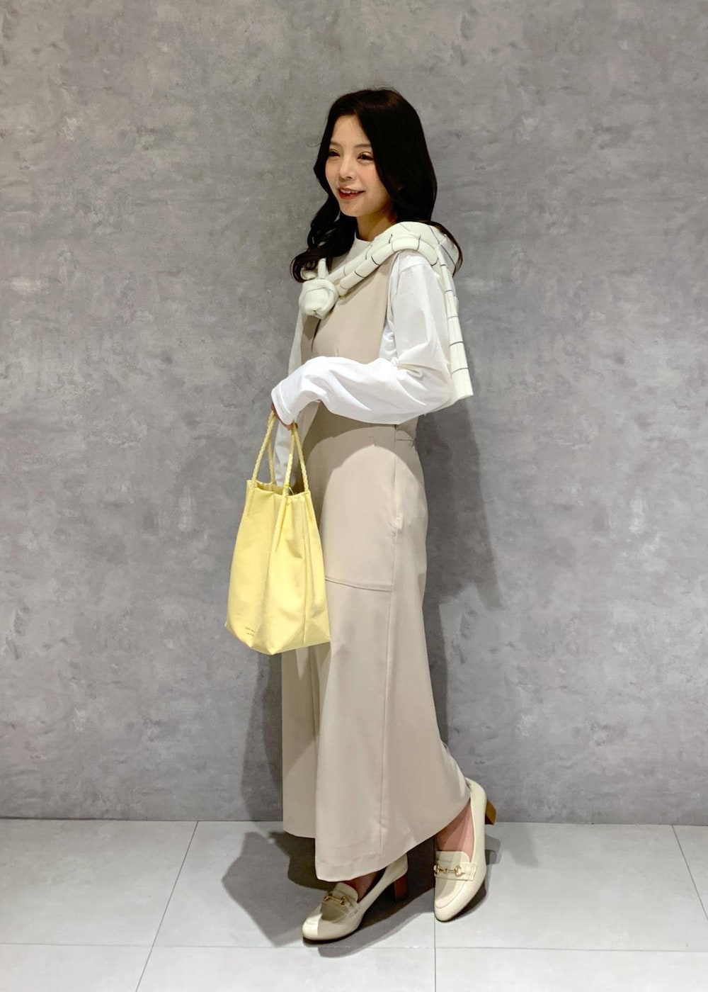ホワイト系のTシャツ/カットソー、イエロー系のトートバッグ、ベージュ系のジャンパースカートを着用したレディースの冬コーディネートの3枚目の写真