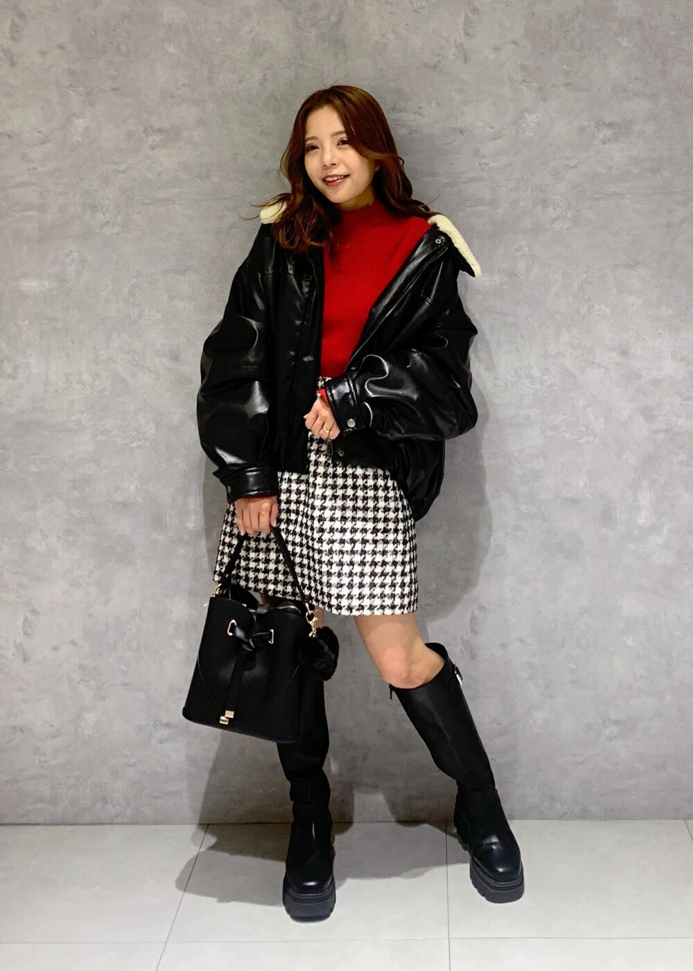 ブラック系のショルダーバッグ、ブラック系のブーツ、レッド系のニット/セーターを着用したレディースの冬コーディネートの2枚目の写真