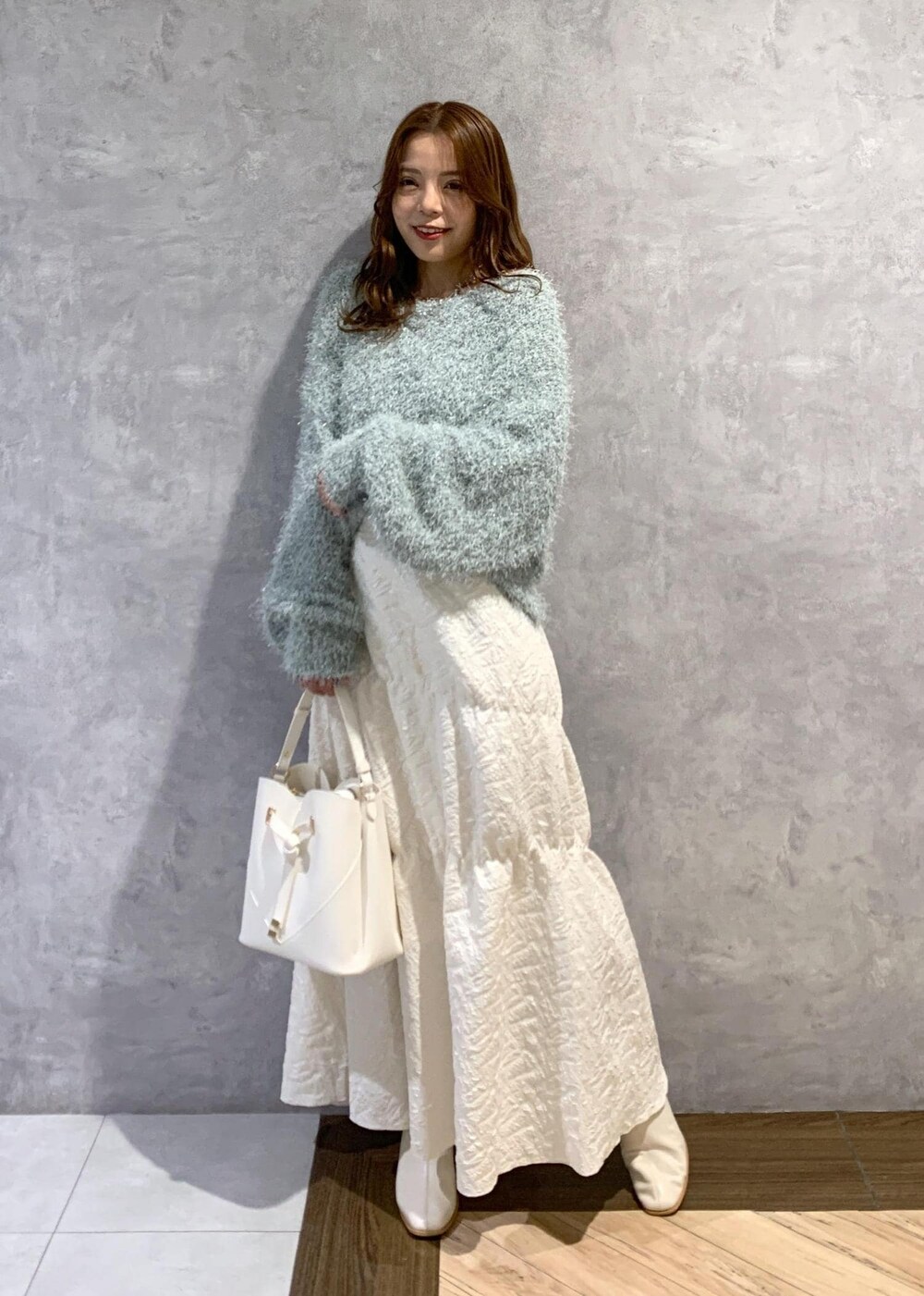 ホワイト系のブーツ、ホワイト系のスカート、グリーン系のニット/セーターを着用したレディースの冬コーディネートの2枚目の写真
