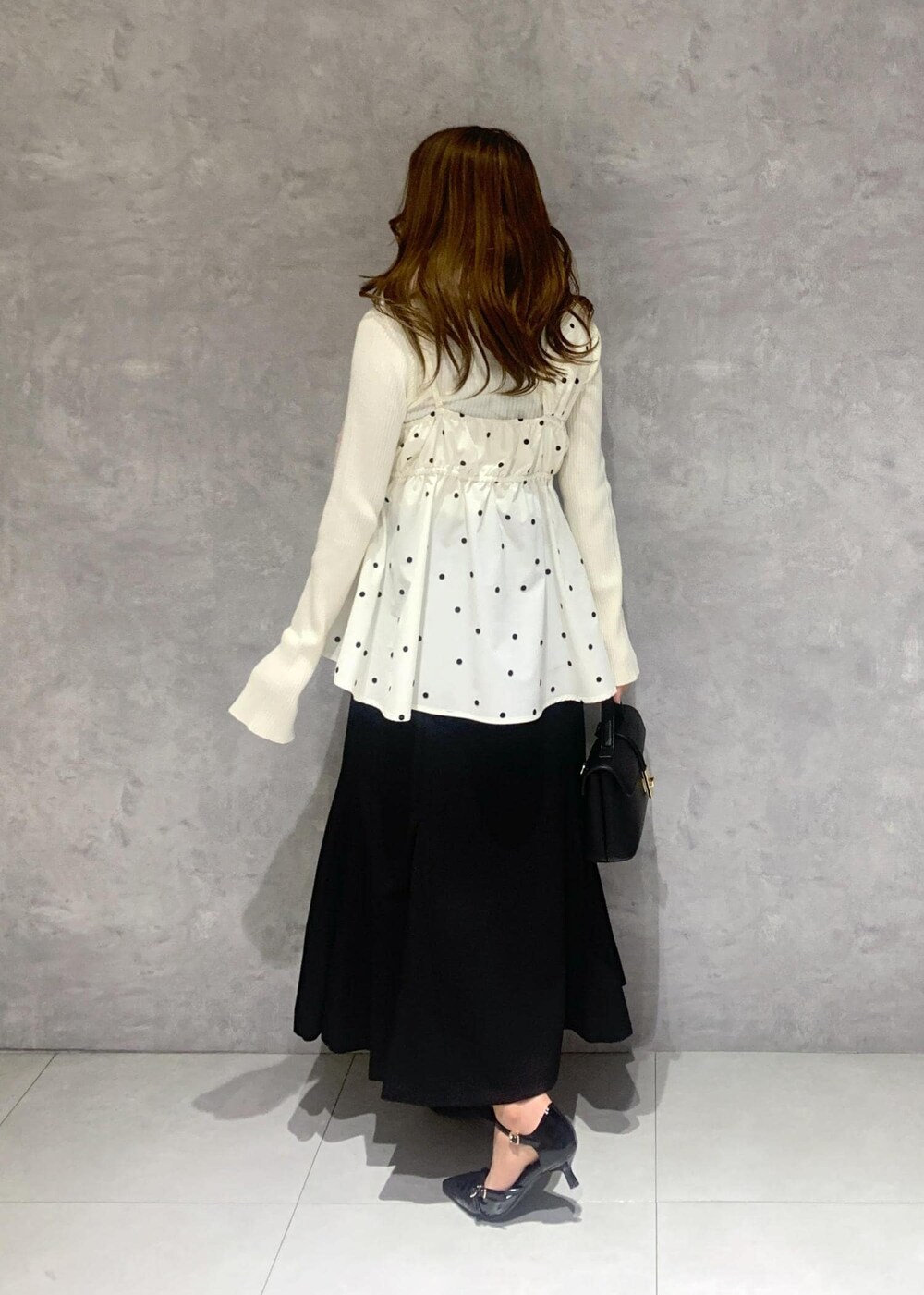 ブラック系のショルダーバッグ、ホワイト系のニット/セーター、ブラック系のスカートを着用したレディースの冬コーディネートの5枚目の写真