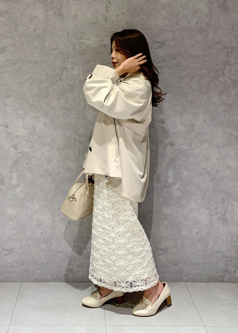 ホワイト系のスカート、ベージュ系のトレンチコート、ベージュ系のニット/セーターを着用したレディースの冬コーディネートの4枚目の写真