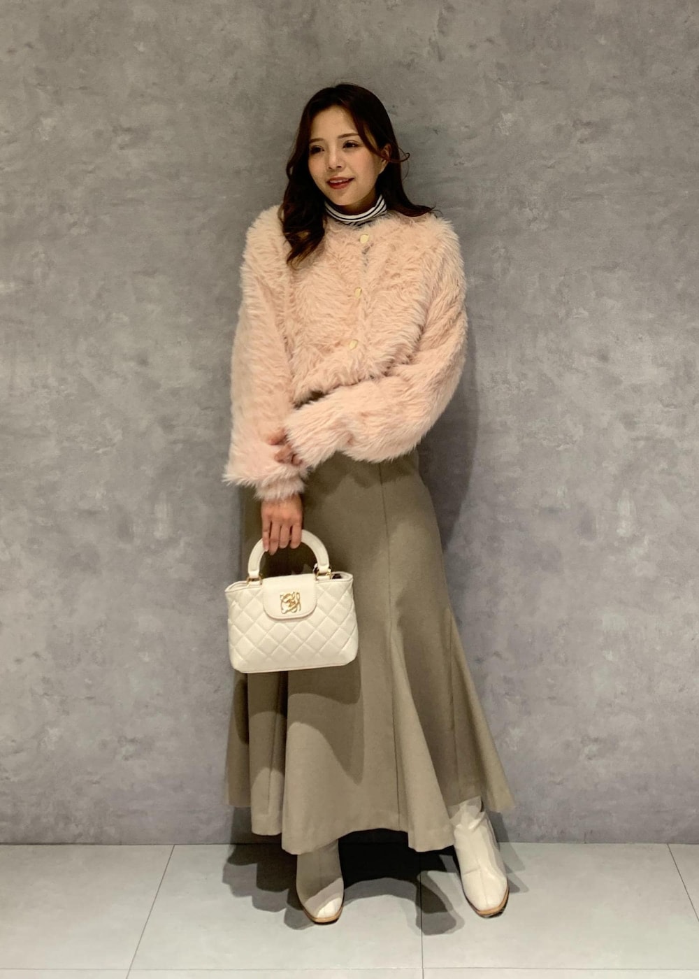 ホワイト系のブーツ、ベージュ系のスカート、ピンク系のカーディガン/ボレロを着用したレディースの冬コーディネートの2枚目の写真