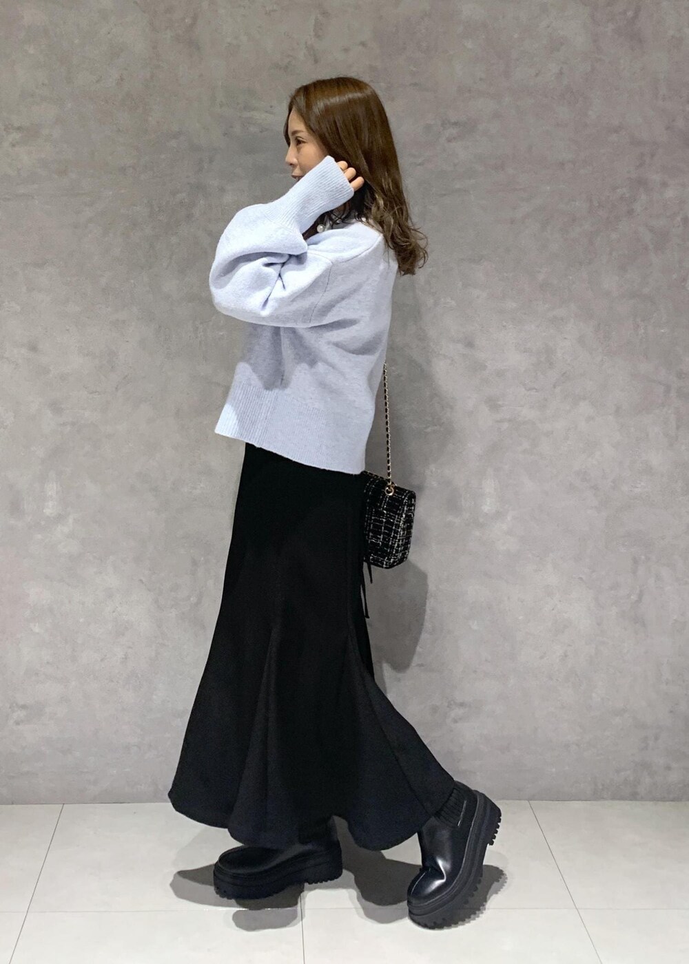 ブラック系のブーツ、ブラック系のショルダーバッグ、ブラック系のスカートを着用したレディースの秋コーディネートの3枚目の写真