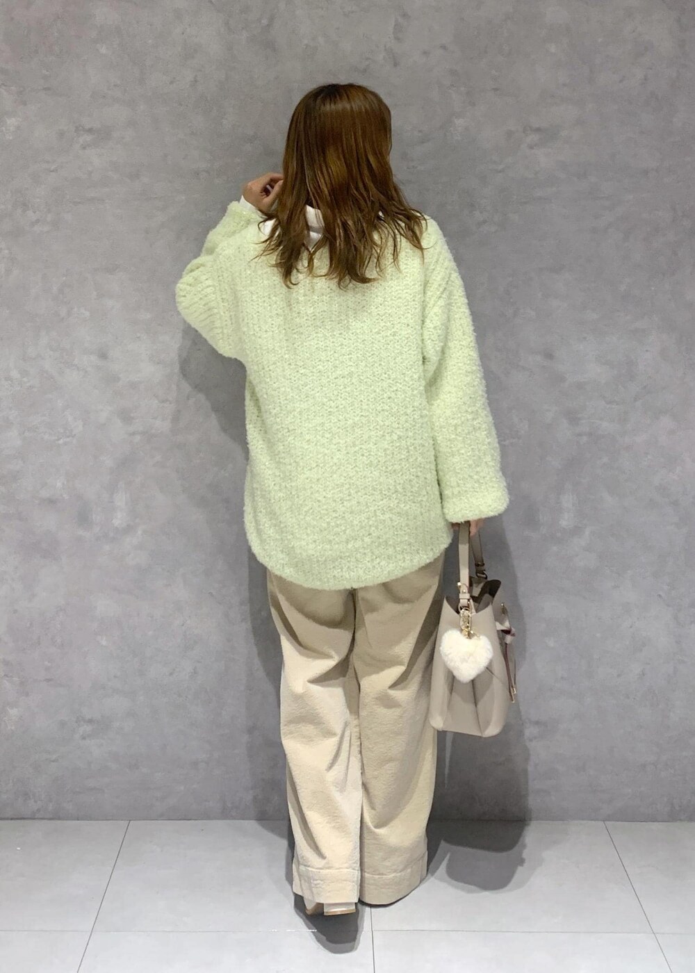 ホワイト系のブーツ、ベージュ系のスラックス、グリーン系のニット/セーターを着用したレディースの秋コーディネートの5枚目の写真