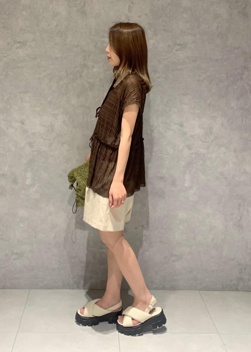 ホワイト系のサンダル、ゴールド系のショルダーバッグ、ブラウン系のTシャツ/カットソーを着用したレディースの夏コーディネートの3枚目の写真