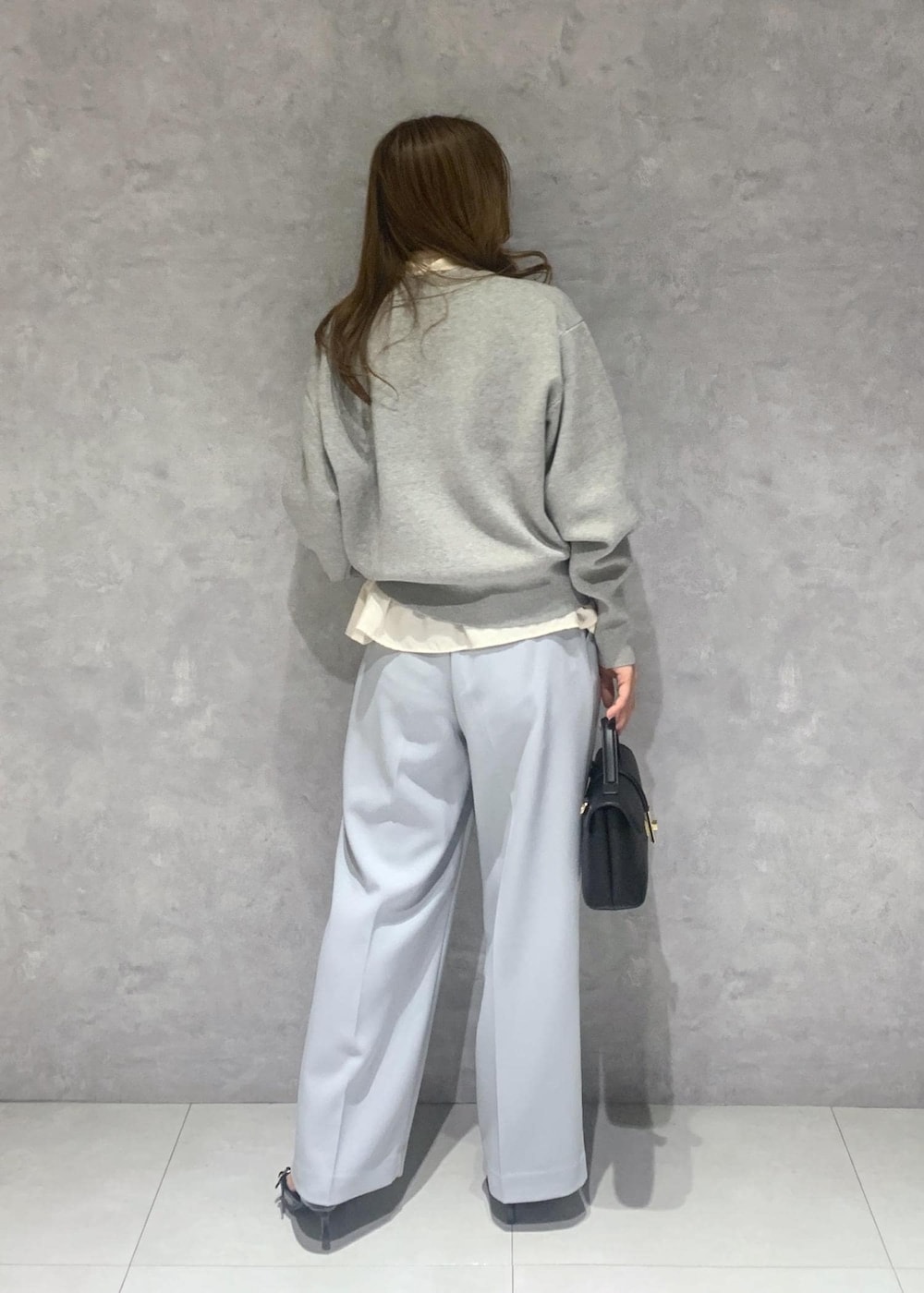 ブラック系のショルダーバッグ、ホワイト系のシャツ/ブラウス、ブルー系のスラックスを着用したレディースの冬コーディネートの6枚目の写真