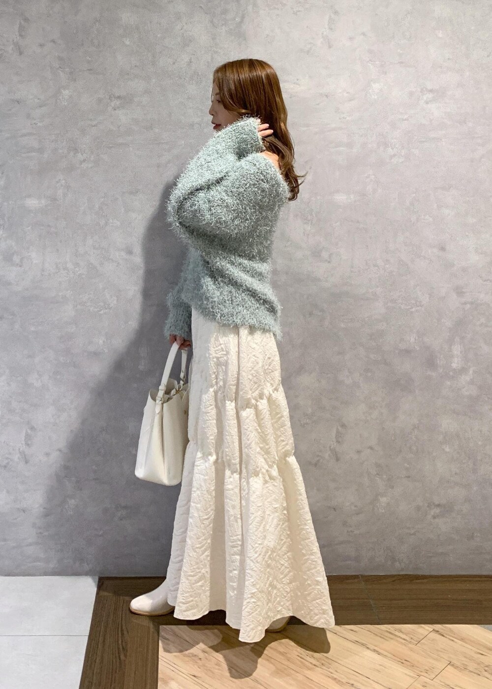 ホワイト系のブーツ、ホワイト系のスカート、グリーン系のニット/セーターを着用したレディースの冬コーディネートの3枚目の写真