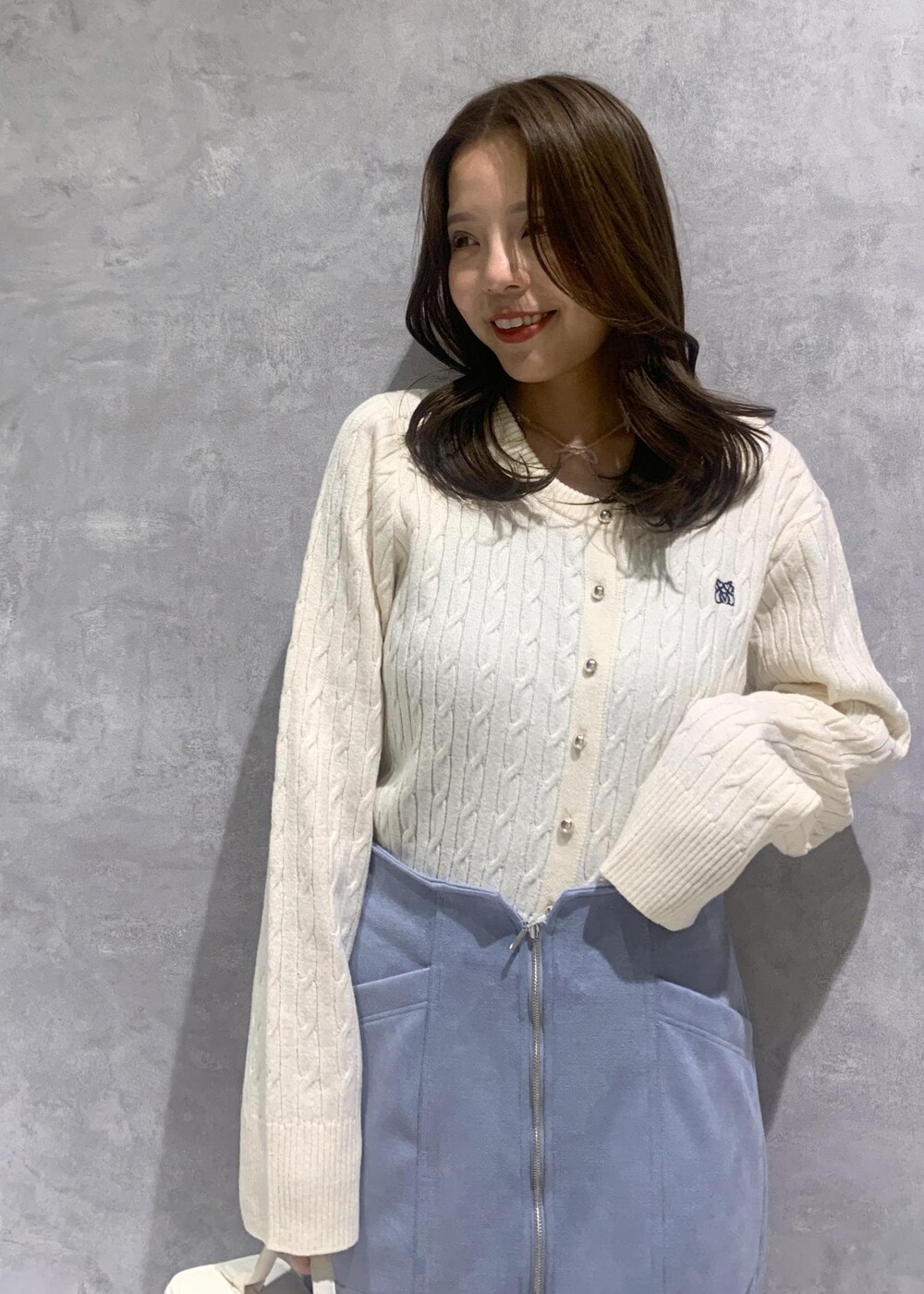 ホワイト系のハンドバッグ、ホワイト系のカーディガン/ボレロ、ブルー系のスカートを着用したレディースの冬コーディネートの7枚目の写真