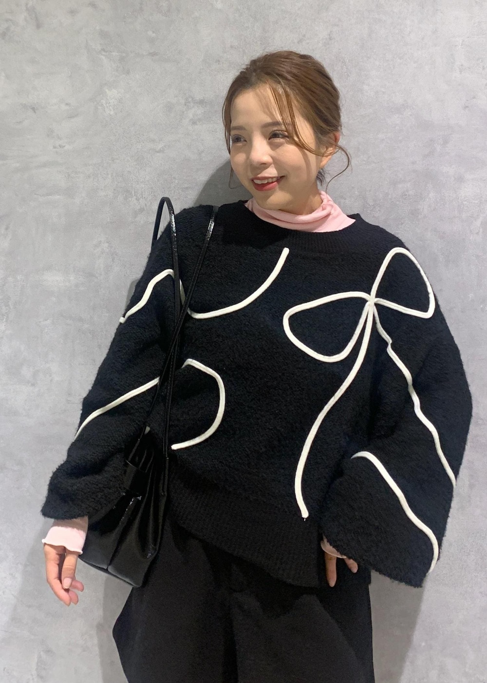 ブラック系のショルダーバッグ、ブラック系のブーツ、ブラック系のニット/セーターを着用したレディースの冬コーディネートの7枚目の写真