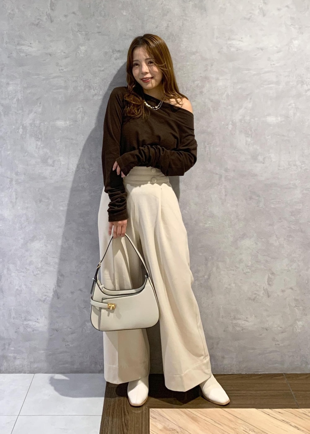 ホワイト系のブーツ、ホワイト系のハンドバッグ、ベージュ系のその他パンツを着用したレディースの秋コーディネートの2枚目の写真