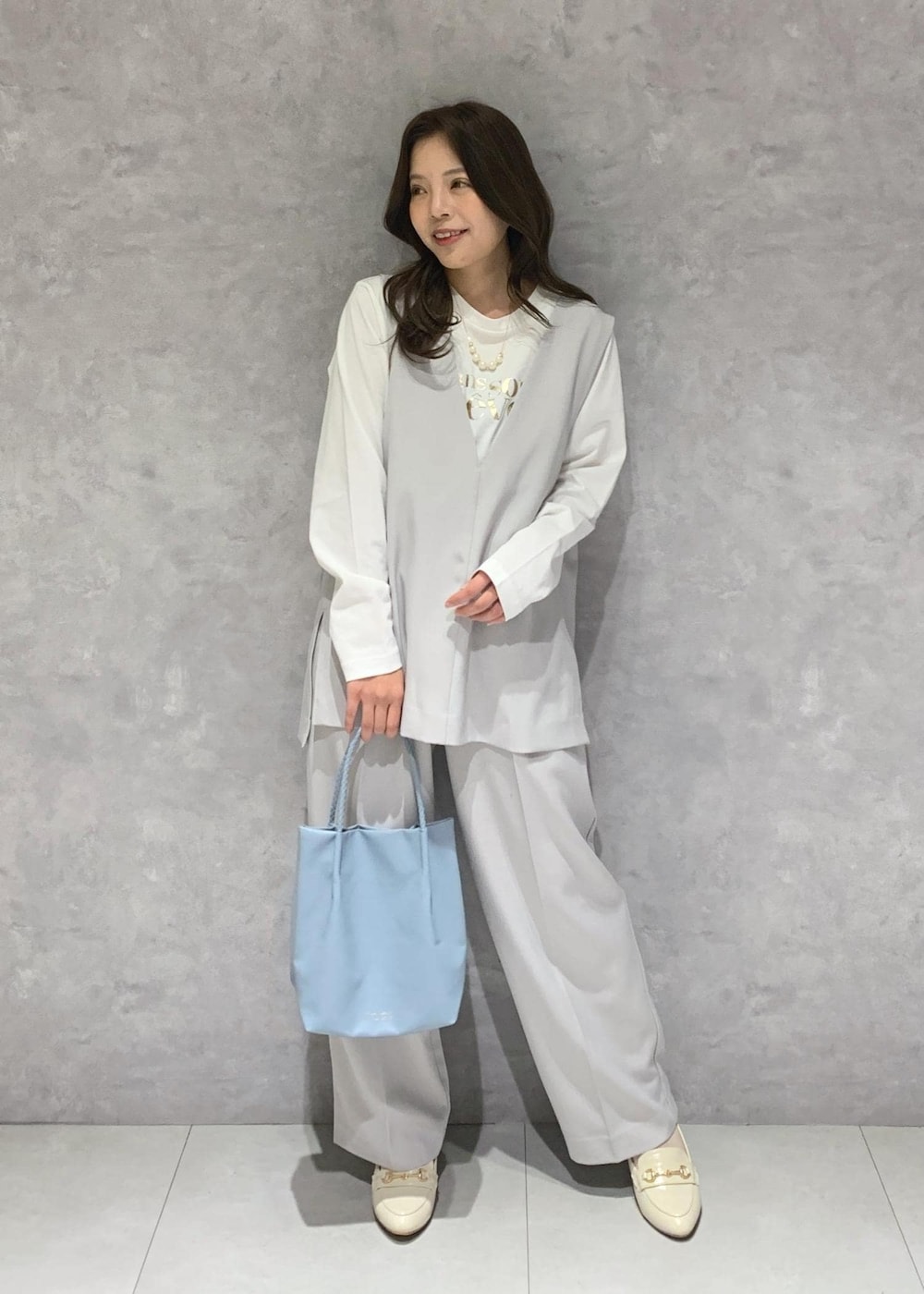ブルー系のトートバッグ、ホワイト系のTシャツ/カットソー、ホワイト系のローファーを着用したレディースの冬コーディネートの2枚目の写真