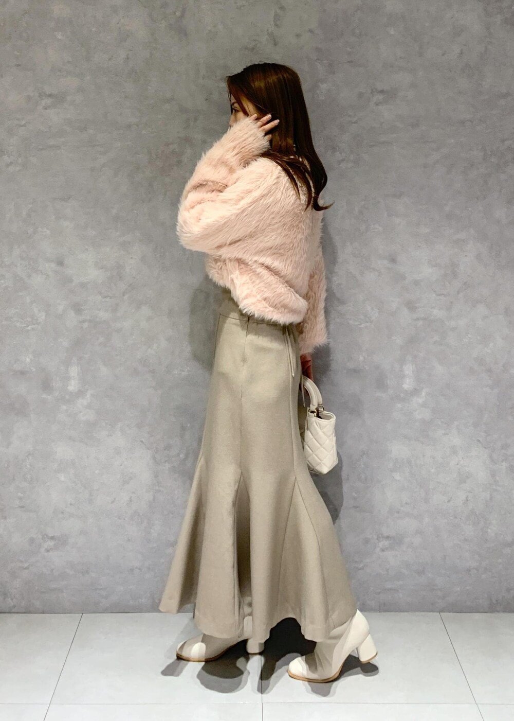 ホワイト系のブーツ、ベージュ系のスカート、ピンク系のカーディガン/ボレロを着用したレディースの冬コーディネートの4枚目の写真